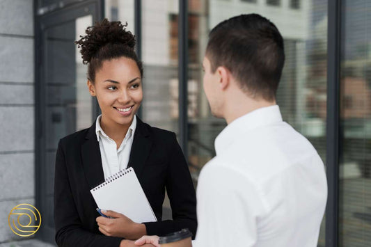 Woman in business attire smiling while holding notebook during one-on-one coaching – 10-Part Flagship Coaching Programme