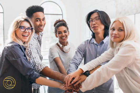 The Strengths Factor of ACTIVE© Leadership – Peas in a Pod: Diverse team smiling with hands stacked in leadership unity