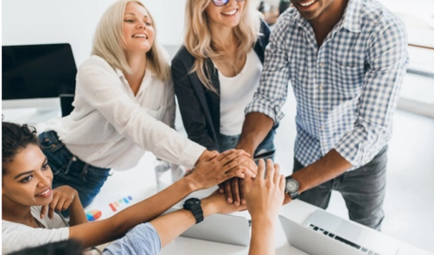 Empowering teams with Strengths - Group Training (2 Days) – diverse team stacking hands in office, collaboration and energy