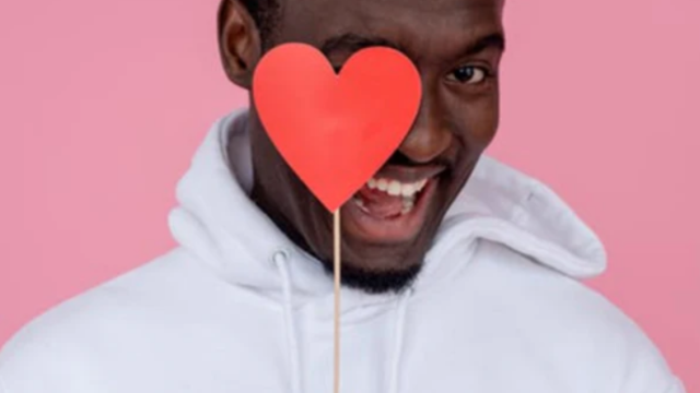 Man with mouth half open smiling with heart on stick infront of right eye