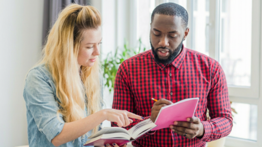 Two people male and female looking at a book and making corrections
