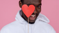 A man with heart shaped on stick holding infront of face and smiling